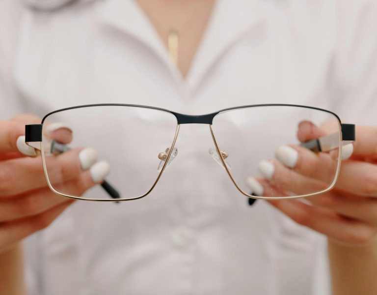 Офтальмолог тримає окуляри у руках