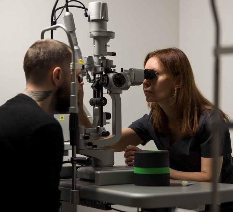 Офтальмолог проводить комплексне обстеження зору дорослому пацієнту в клініці