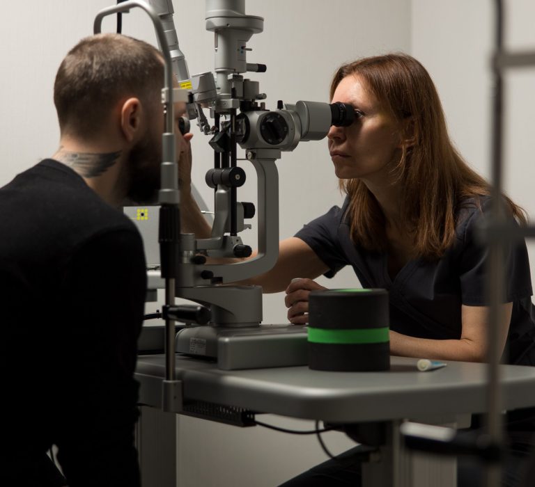 Офтальмолог проводить комплексне обстеження зору дорослому пацієнту в клініці